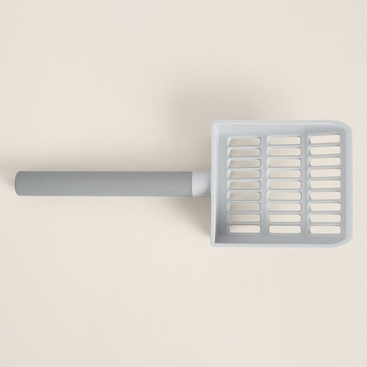 Gray and white plastic scoop with slots on a beige background.